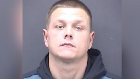 A mugshot of a man with short light brown hair. He is wearing a blue hoodie.