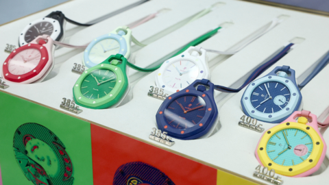 An assortment of pocket watches in different colours lie on a stand