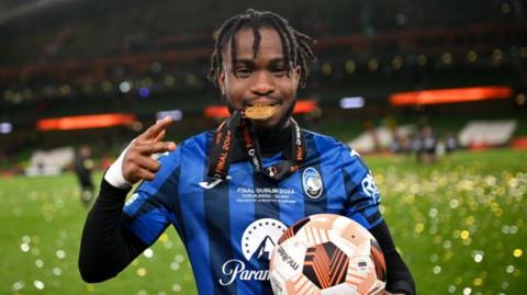 Ademola Lookman celebrates Atalanta's Europa League win by biting on his medal while holding the match ball