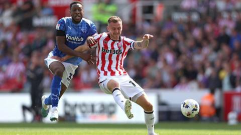 Ebou Adams is held off the ball by Stoke's Ben Wilmot