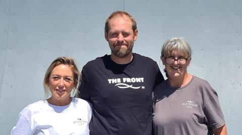 Stuart Welstead stands with two female members of staff on one of the skate ramps at the skatepark