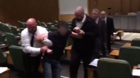 A protester is led out of the council chamber by security staff