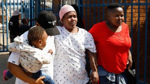 Family member comfort each other as they leave after undergoing a process of identifying bodies at Dieokloof Forensic Laboratory in Soweto on September 1, 2023