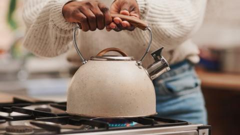 Woman boiling water on a gas stove