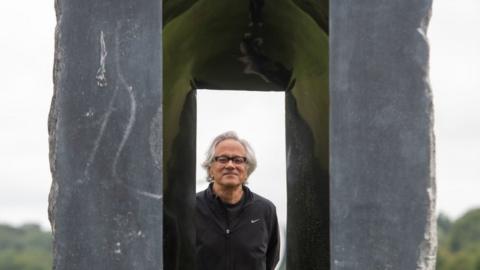 Artist Anish Kapoor looks through one of his sculptures at Houghton Hall