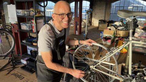 Swindon Welcomes Ukraine treasurer David Thrower working on a bike