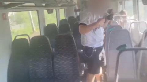 Man with face blurred and arms raised inside of train carriage