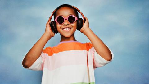 Child wearing sunglasses and wearing headphones.