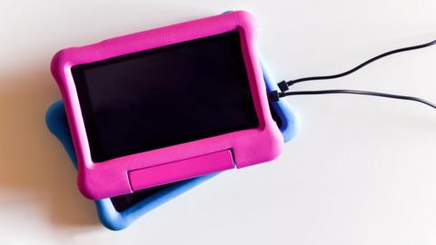 Two tablets with blue and pink protective covers on charge.
