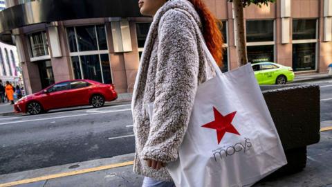 A female shopper in a furry grey coat carries a Macy's bag on Market Street in San Francisco, California, US, on Wednesday, Nov. 13, 2024. 