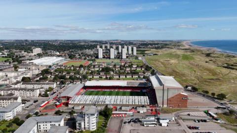 An earlier view of the Aberdeen coast, showing Aberdeen FC's Pittodrie Stadium, high-rise blocks, and the sea.