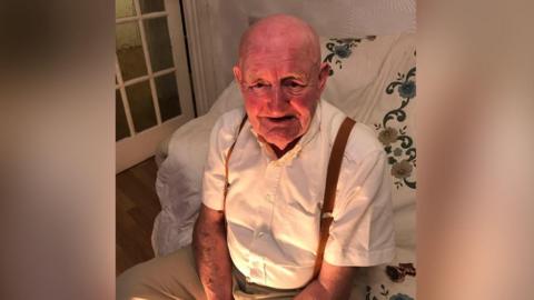 Joe Shaw smiling while sitting on a sofa