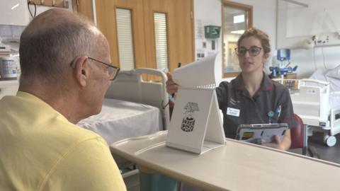 A Dementia Research Nurse turns a flip chart of images for a clinical trial participant to identify.