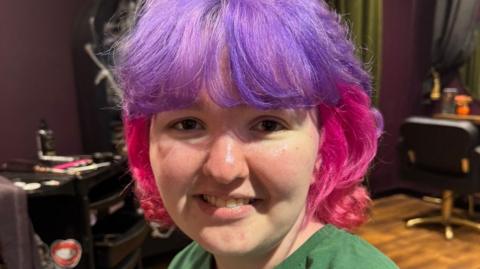 Lillia Jakeman smiling at the camera with purple and pink coloured hair.