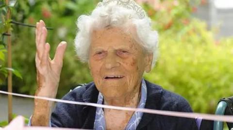 Close up shot of Ethel Catherham wearing a tiara with 115 written on it.