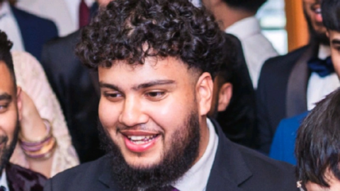 Alvi Choudhury is wearing a suit and has dark short curly hair and a dark full beard