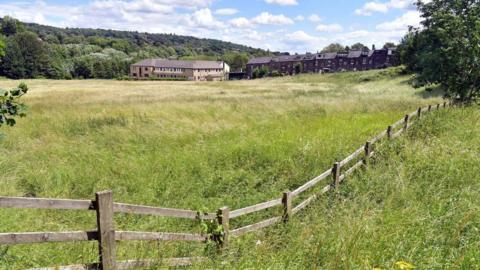 A view of the land on Coolgardie Farm. The site is currently an empty field, with housing in the distance.