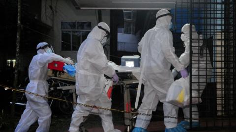 A picture of 3 people wearing white suits. They have masks on.