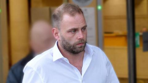 Sam Barber outside court wearing an open-necked white shirt