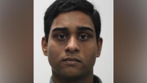Dihan Rahman - a young man with short, black hair looks into a camera for a police custody shot