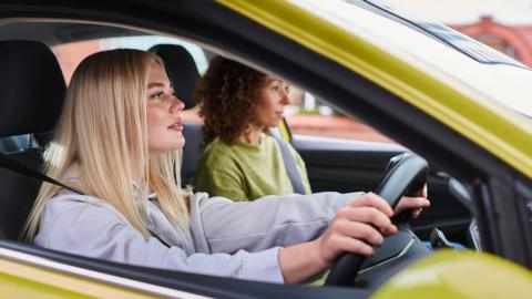 A young female learner driver in a yellow car 