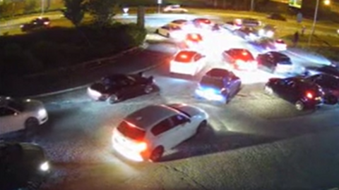 A still from a police video showing numerous cars converging on a junction at night.