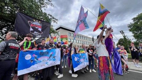 The Pride march at Newcastle Civic Centre. Crowds of people wearing brightly coloured clothes are waving flags in support of the LGBTQ+ community.