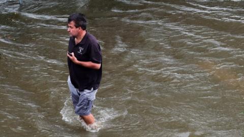 Chris Ladner walks through a flooded area near Lake Pontchartrain as Storm Barry approaches in Mandeville, La 13 July 2019