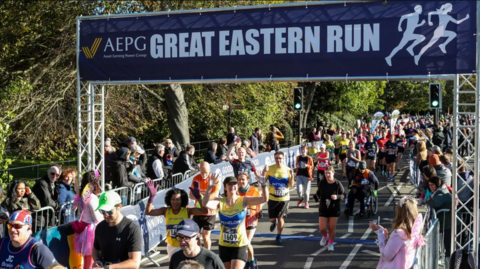 Runners running under a large blue sign that says "Great Eastern Run".