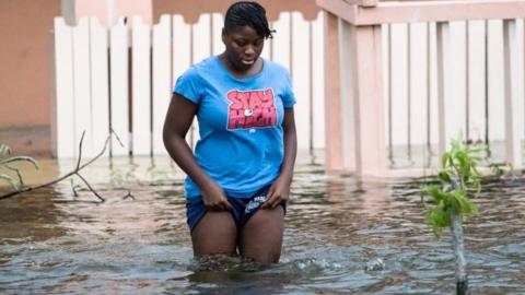 A woman stands in a flooded street in the Bahamas as Hurricane Dorian hits