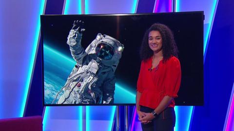 Nina in the studio with an astronaut in the screen