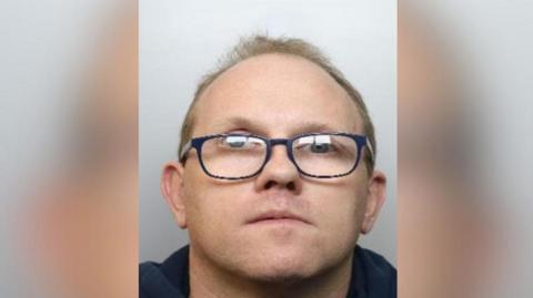 A mugshot of Neil King. A bespectacled man with a receding hairline.