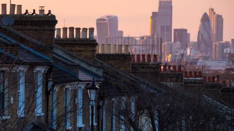 Row of houses in the foreground. In the background there is a skyline of buildings in the City of London. 
