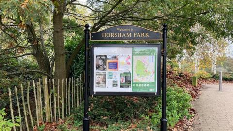 A sign for the entrance to Horsham Park with community notices and a map. 