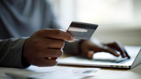 A hand holding a credit card