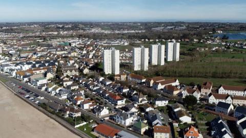 Aerial view of houses and flats in Jersey with the beach in the foreground.