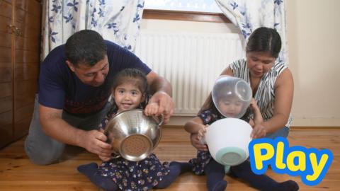 Mother, father and two children playing with mixing bowls together.
