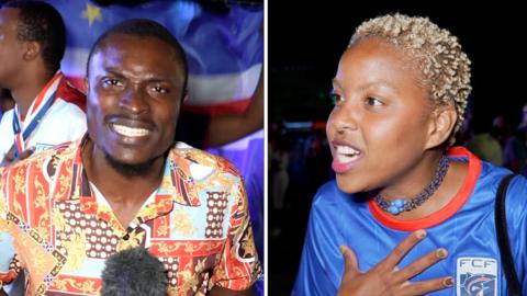 A presenter speaks to camera in a colourful shirt, next to a football fan passionately touching her chest and speaking.