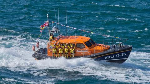 RNLI lifeboat at sea with crew waving