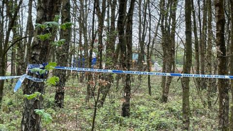 Police tent and cordon wrapped around trees