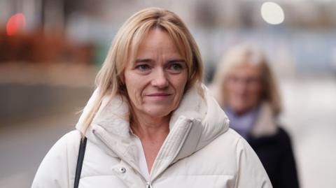 Sandie Peggie - a woman with blond hair and a white jacket, arriving at a employment tribunal hearing