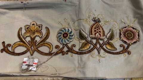 A floral design in brown and gold on a piece of fabric.  There are also blue and red colours.