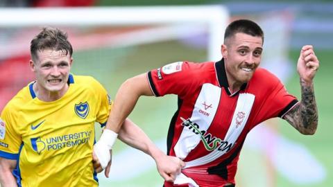 Terry Devlin (left), of Portsmouth, battles for the ball against Dominic Jefferies, of Lincoln City