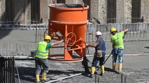 Construction workers pour concrete for residential buildings under construction at a large construction site in Munich, southern Germany, May 11, 2022