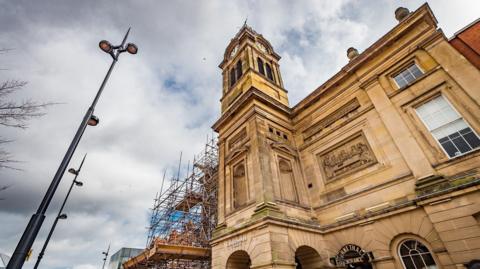 The light coloured stone of the Guildhall Theatre building with scaffolding over part of it