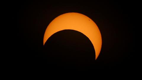 The moon passes the sun during an annular solar eclipse, in Las Horquetas, Santa Cruz, Argentina. The orange sun looks like a "C" on its side as the moon passes it.