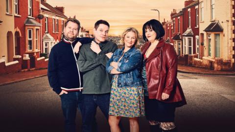 The main cast of Gavin & Stacey stand on the street in Barry, and smile towards the camera. From left to right: James Corden, Ruth Jones, Joanna Page and Mathew Horne.