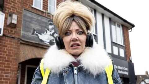 Diane Morgan as Mandy pulling a disgusted face while wearing headphones