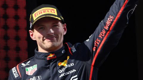 Max Verstappen raises his left arm in celebration on the podium after winning the Emilia-Romagna Grand Prix