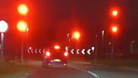 A car brakes as it approaches red traffic lights